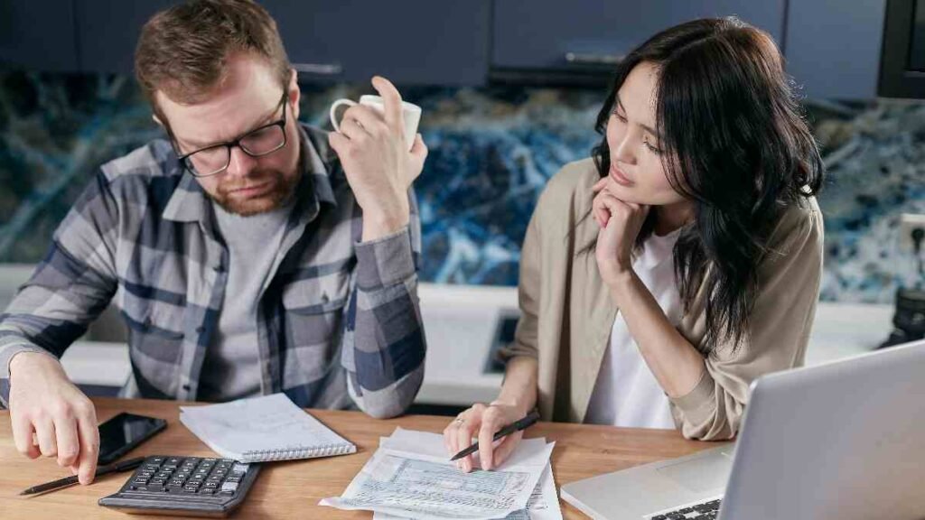 Writing down total debt numbers in a budget notebook with a calculator