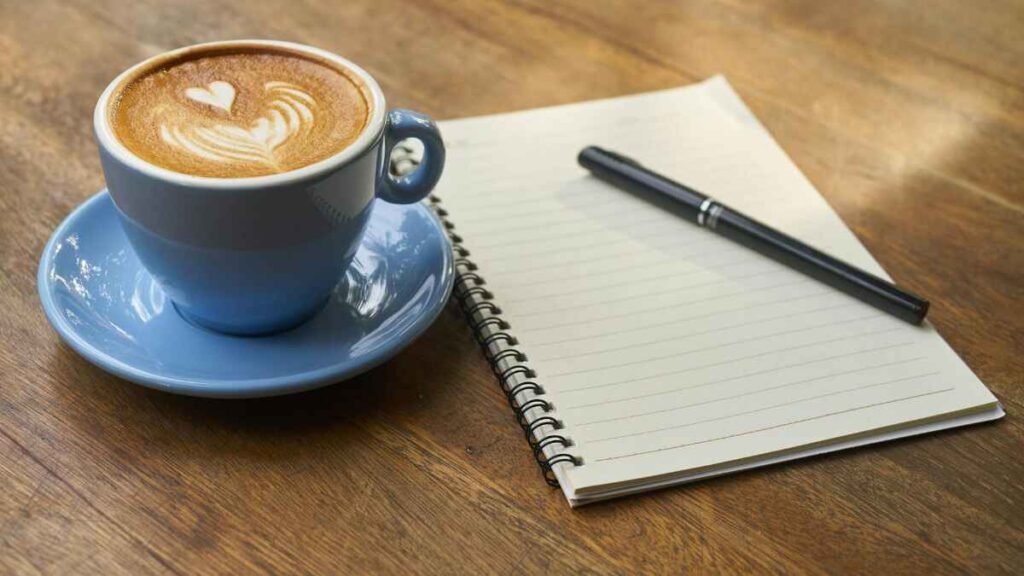 Open notebook and coffee cup for planning loud budgeting scripts and financial goals