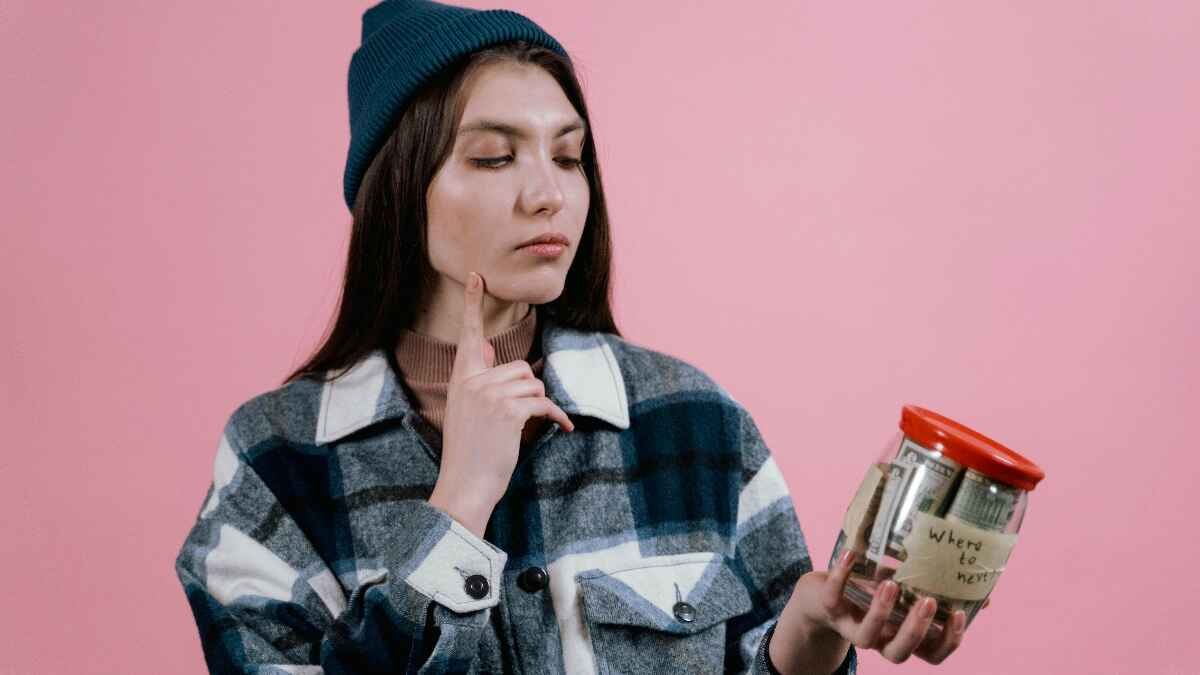 Woman holding money jar planning no spend month challenge
