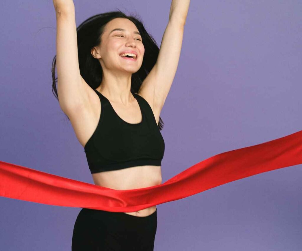 Happy woman crossing a red finish line symbolizing becoming debt-free and achieving financial goals.