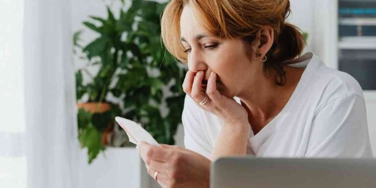 Stressed woman looking at bills and laptop figuring out a bare bones budget for low income.