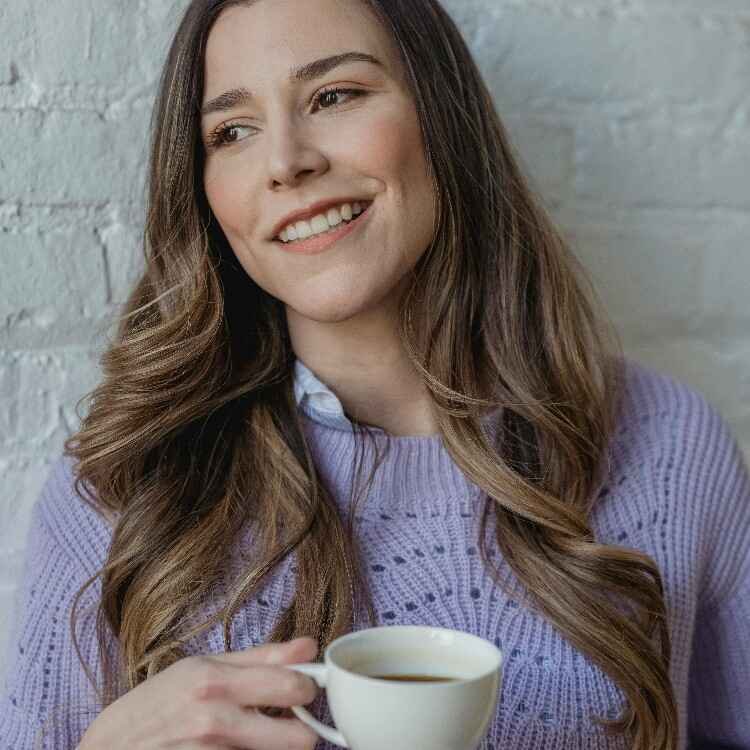 Smiling woman drinking coffee representing financial peace and hope after successfully using a bare bones budget.