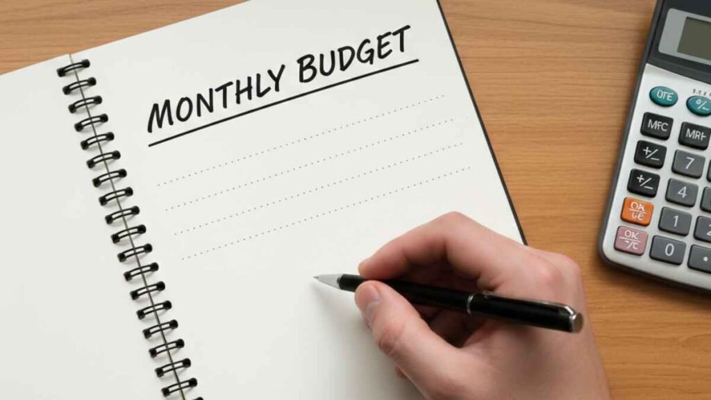 Hand writing a monthly budget plan in a notebook representing a survival budget example.